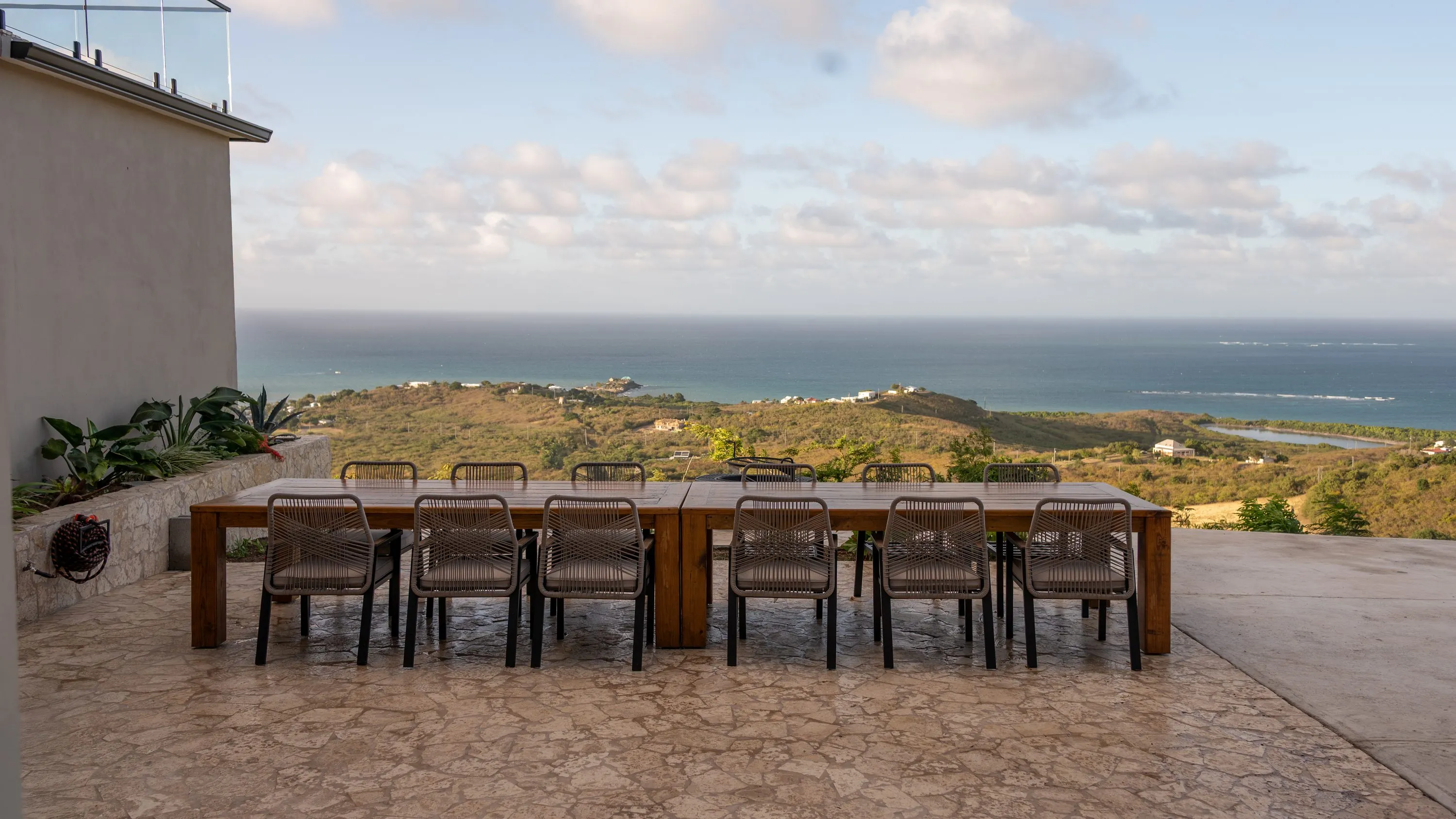 Long outdoor dining table on a stone terrace overlooking the Caribbean Sea and Buck Island from a hillside on the east end of St. Croix